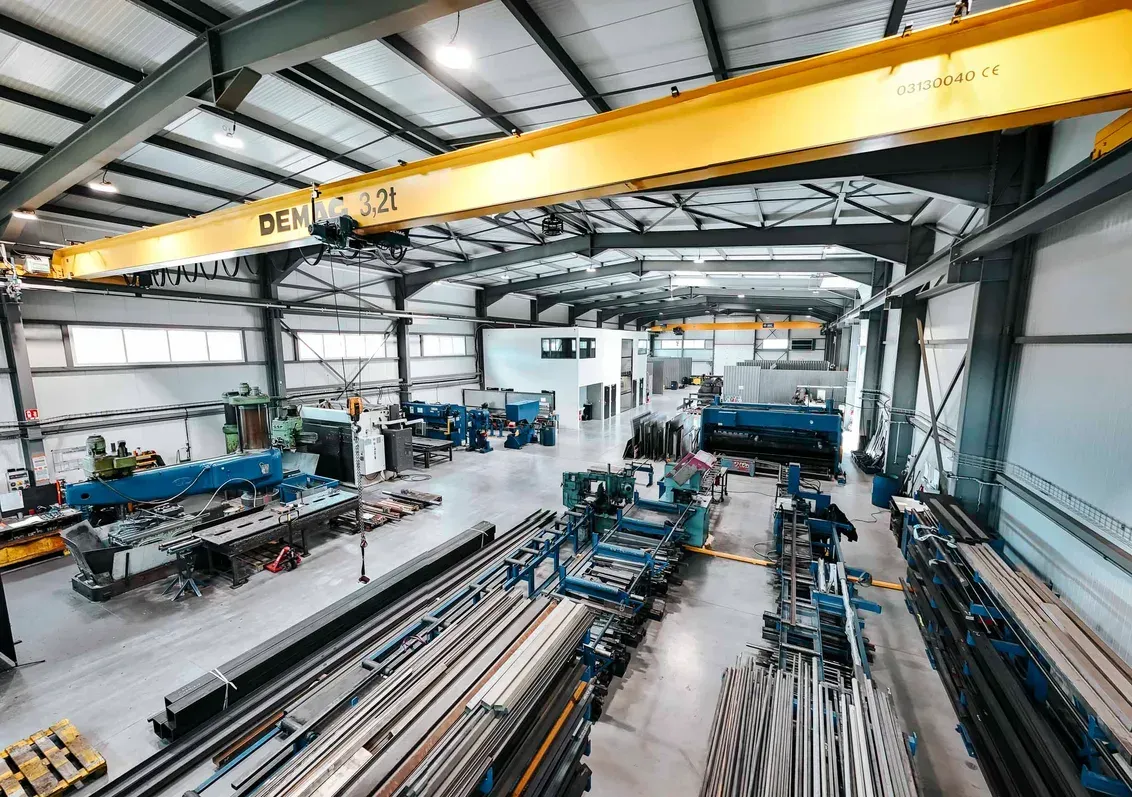 Vue intérieure de l’atelier CMC à Perrignier : pont roulant jaune et postes de travail alignés