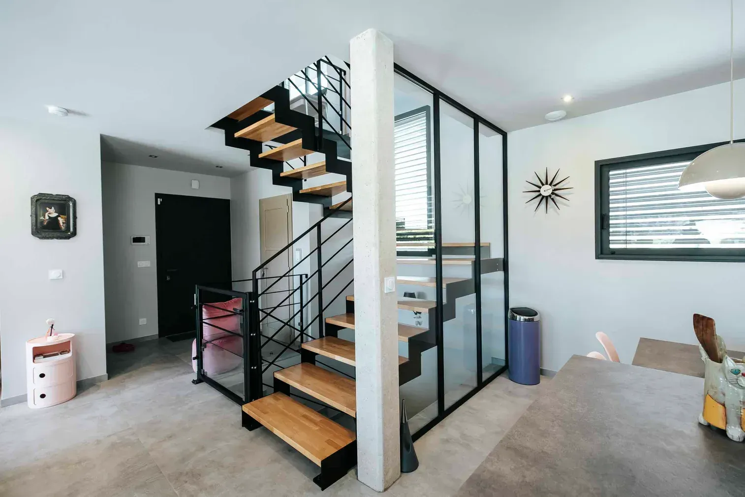 Escalier métallique et verrière d’intérieur séparant l’entrée du séjour