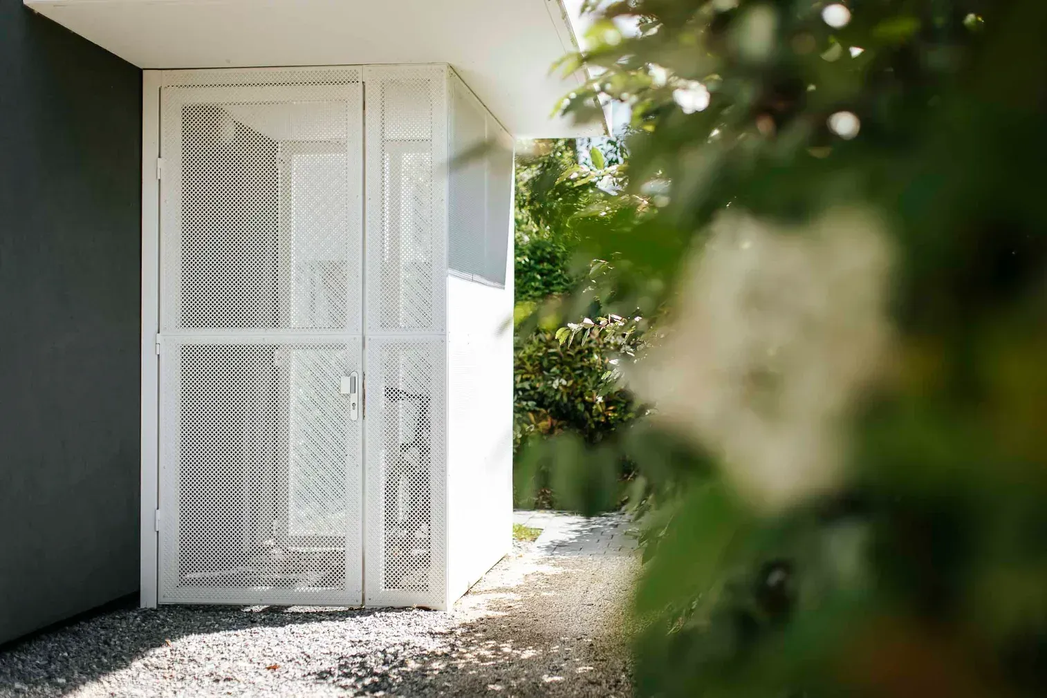 Portillon métallique en tôle perforée blanche dans un jardin